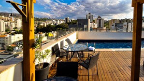 A rooftop terrace with a pool, wooden deck, and outdoor seating area. - Esuites Virginia Luxemburgo BH (Belo Horizonte)