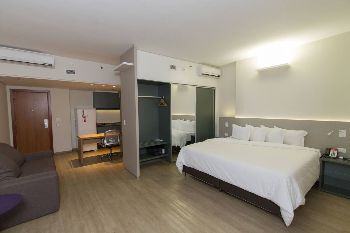 Een hotelkamer met een bed, een bureau, een stoel, een kledingkast en een kleine tafel met een telefoon.
