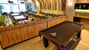 A billiards table with balls, a pool table, and a seating area with tables and chairs. - Esuites Virginia Luxemburgo BH (Belo Horizonte)