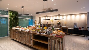 A buffet area with various food items and a coffee station. - Esuites Virginia Luxemburgo BH (Belo Horizonte)