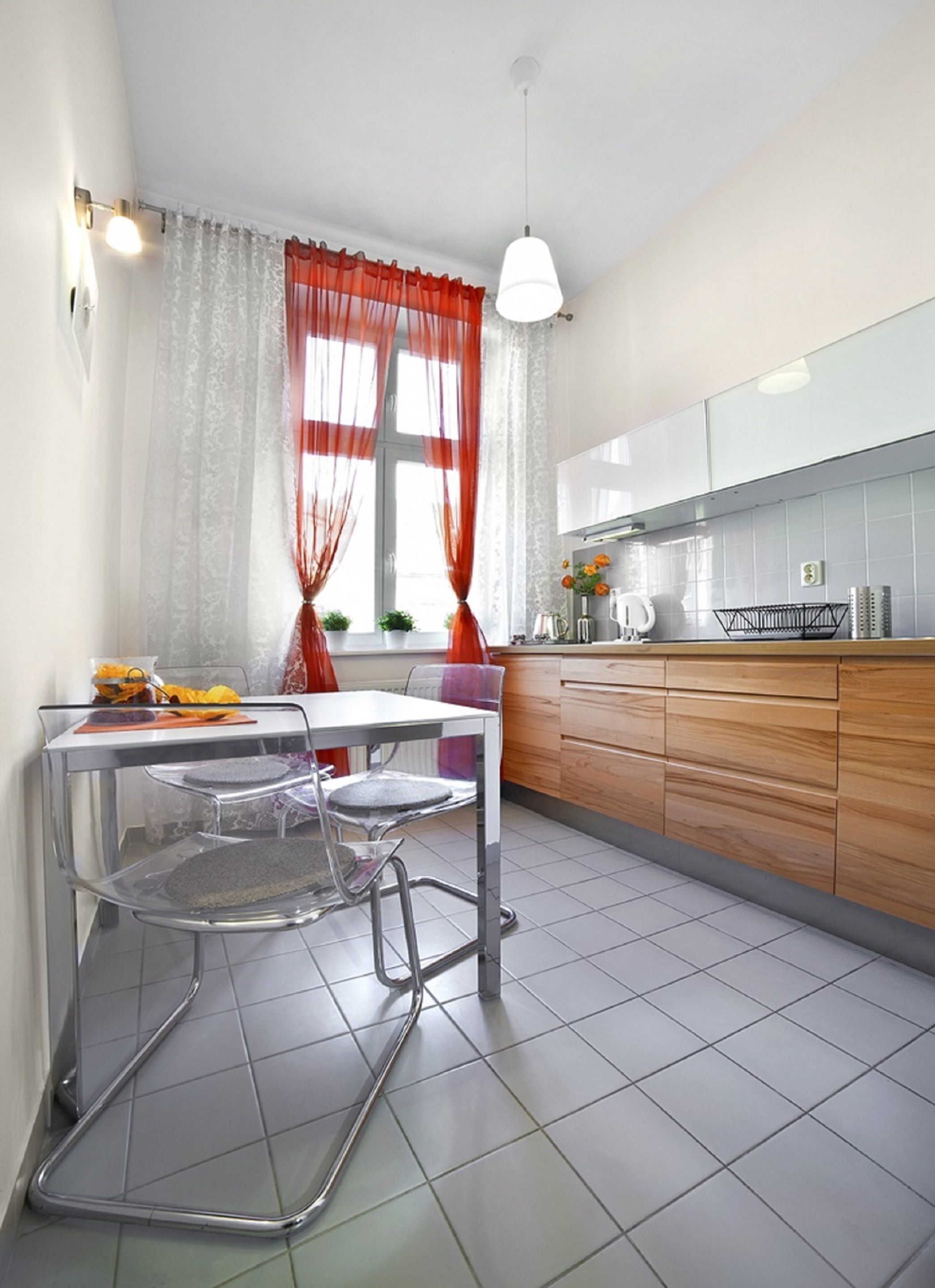 A modern kitchen with a dining table, chairs, and a window with curtains.