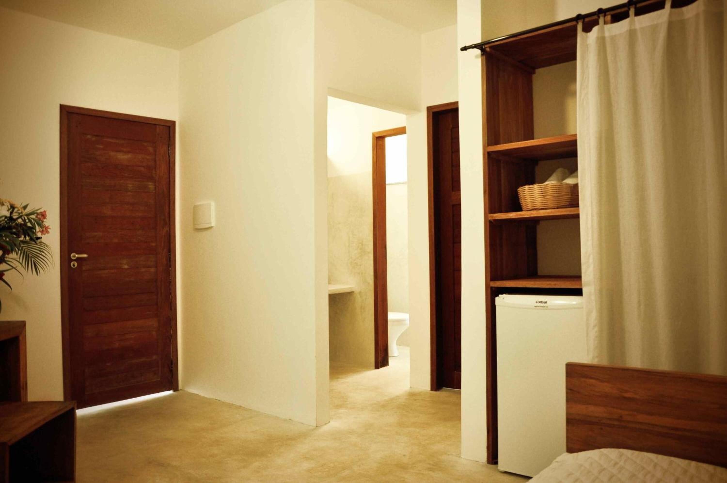A bedroom with a wooden bed, a white bedside table, a small desk, a chair, a wooden wardrobe, and a white radiator.