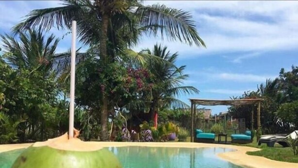 A pool with a wooden deck, surrounded by palm trees and a gazebo. - Pousada dos Ponteiros (São Miguel do Gostoso)