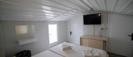 Camera d'albergo con un letto, una TV a parete, una piccola scrivania e una finestra.