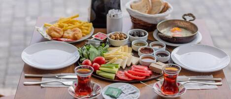 A table set with various food items, including bread, eggs, and vegetables, along with two glasses of tea.
