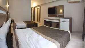Quarto de hotel com duas camas, uma escrivaninha, uma cadeira, uma televisão e um espelho.
