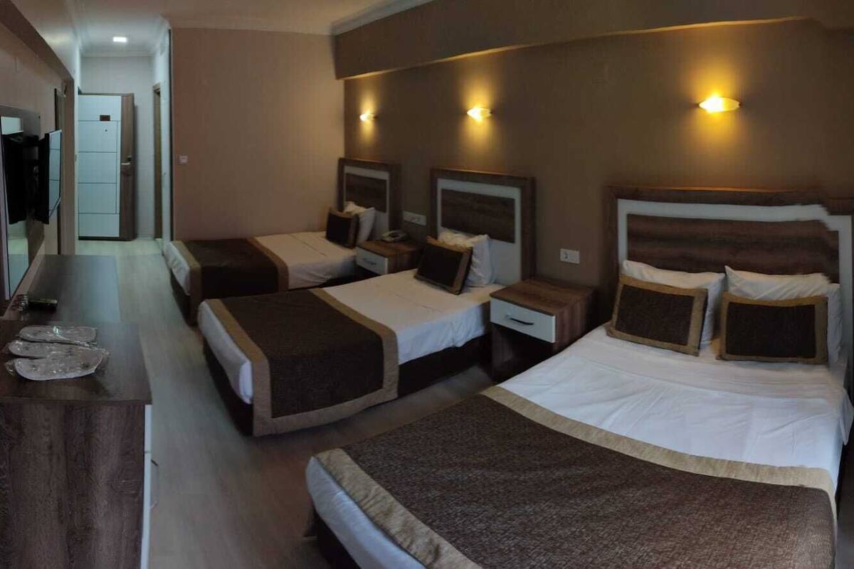 A hotel room with two single beds, a wooden dresser, and a small desk with a mirror.