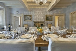 A formal dining room with a long table set for a meal, flanked by chairs, and a fireplace in the center. - Villa Melangola (Camaiore)
