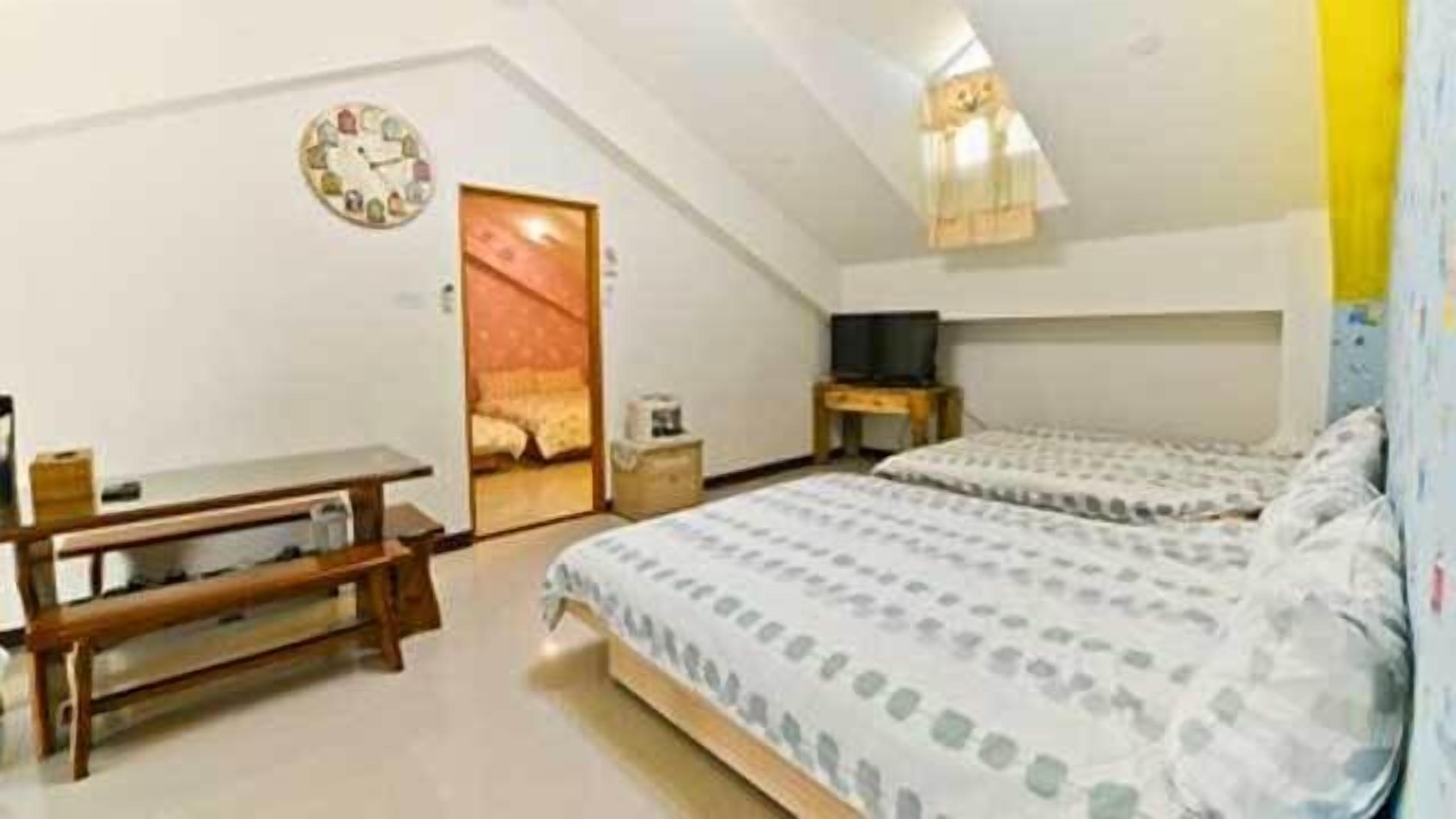 Un dormitorio con dos camas, un escritorio, un televisor y un reloj en la pared.