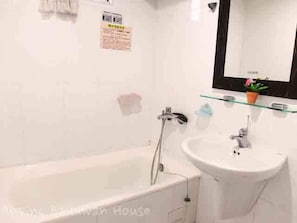 A bathroom with a bathtub, a sink, and a mirror.