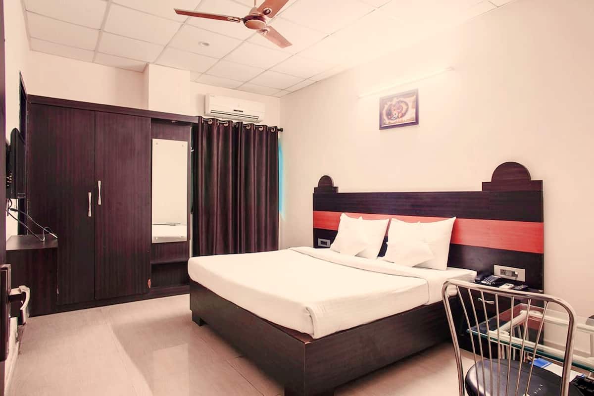 A hotel room with a bed, a wardrobe, a ceiling fan, and a wall-mounted air conditioner.