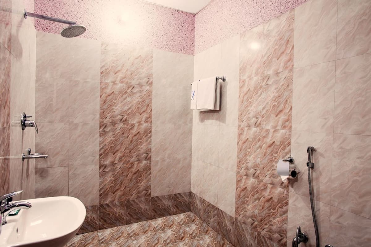 A modern bathroom with a marble shower, a sink, and a towel rack.
