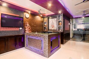 A reception area with a marble counter, ceiling fans, a clock, and decorative items. - GenX Sundaram Haldwani (Haldwani)