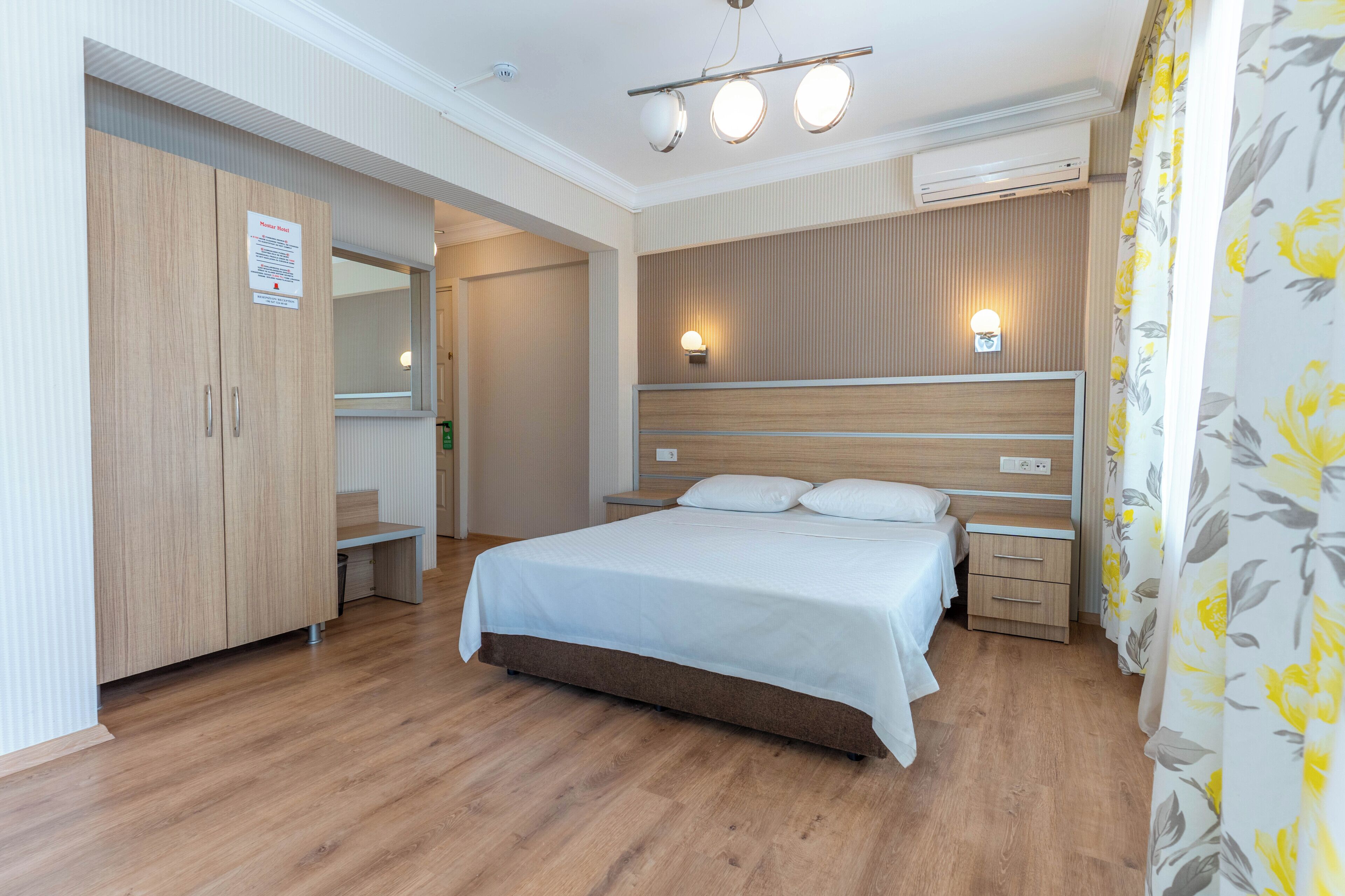 Ein Schlafzimmer mit einem Bett, Nachttischen, einem Kleiderschrank, einem Spiegel und einer Wandleuchte.