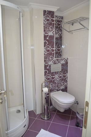 A bathroom with a glass-enclosed shower, a toilet, and a sink.