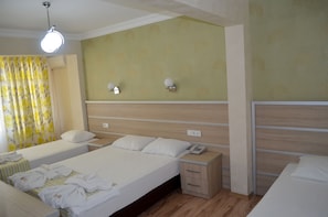 A hotel room with two single beds, a bedside table with a phone, and a wall-mounted light fixture.