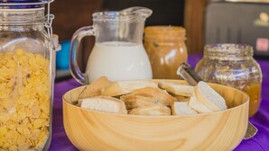 A breakfast table with a bowl of sliced bread, a pitcher of milk, and a jar of honey. - The Trip Hostel (Punta del Este)