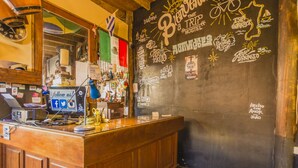 A bar area with a wooden counter, a computer monitor, and various items on the wall. - The Trip Hostel (Punta del Este)