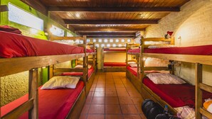A dormitory room with bunk beds, a tiled floor, and a brick wall. - The Trip Hostel (Punta del Este)