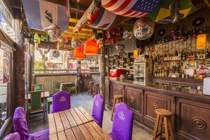 Un bar con mobiliario de madera, barra y estanterías llenas de botellas.