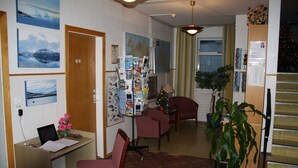 Ein Zimmer mit Schreibtisch, Stühlen, einer Topfpflanze und einer Treppe.