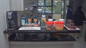 A kitchen counter with coffee makers, tea bags, and food containers. - Fedha Residences (Nairobi)