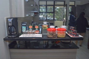Una encimera de cocina con cafeteras, bolsitas de té y recipientes de comida.