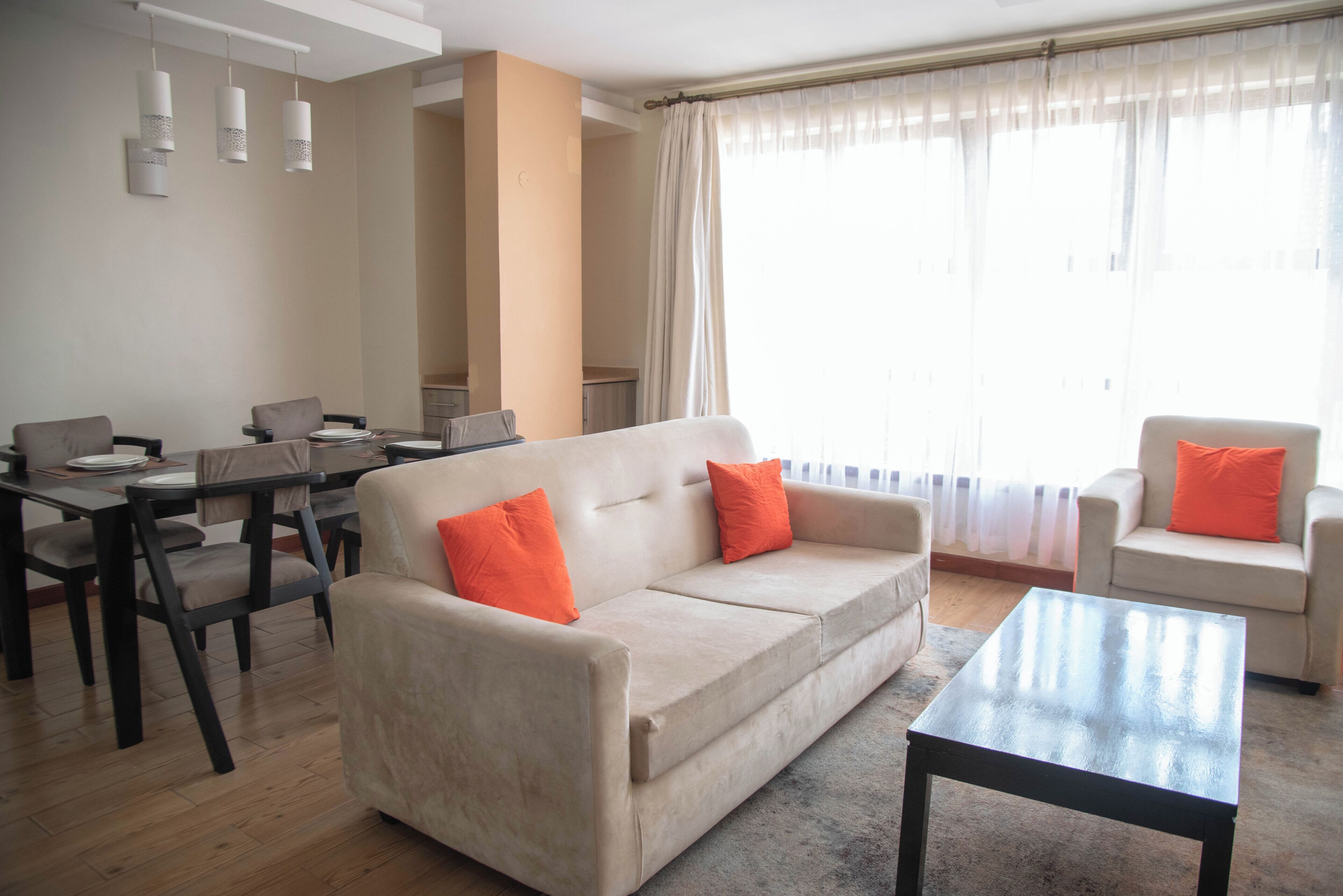 A modern living room with a sofa, armchairs, a dining table, and a coffee table.
