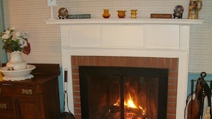 A living room with a fireplace, a wooden cabinet, a plaid sofa, and a patterned rug.