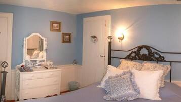 A bedroom with a bed, dresser, and wall-mounted light fixture.