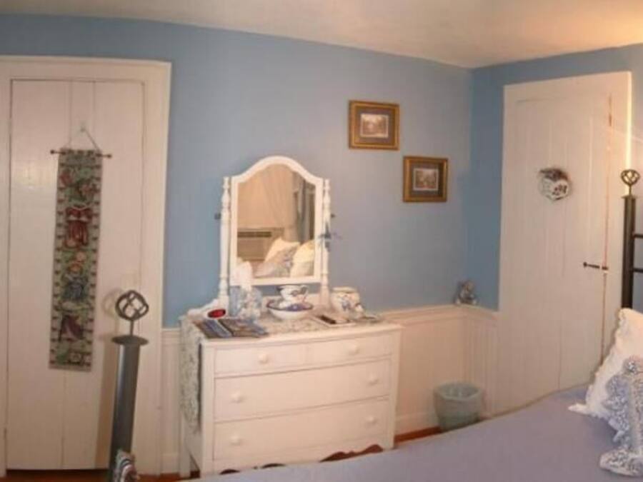 A bedroom with a bed, dresser, and wall-mounted light fixture.