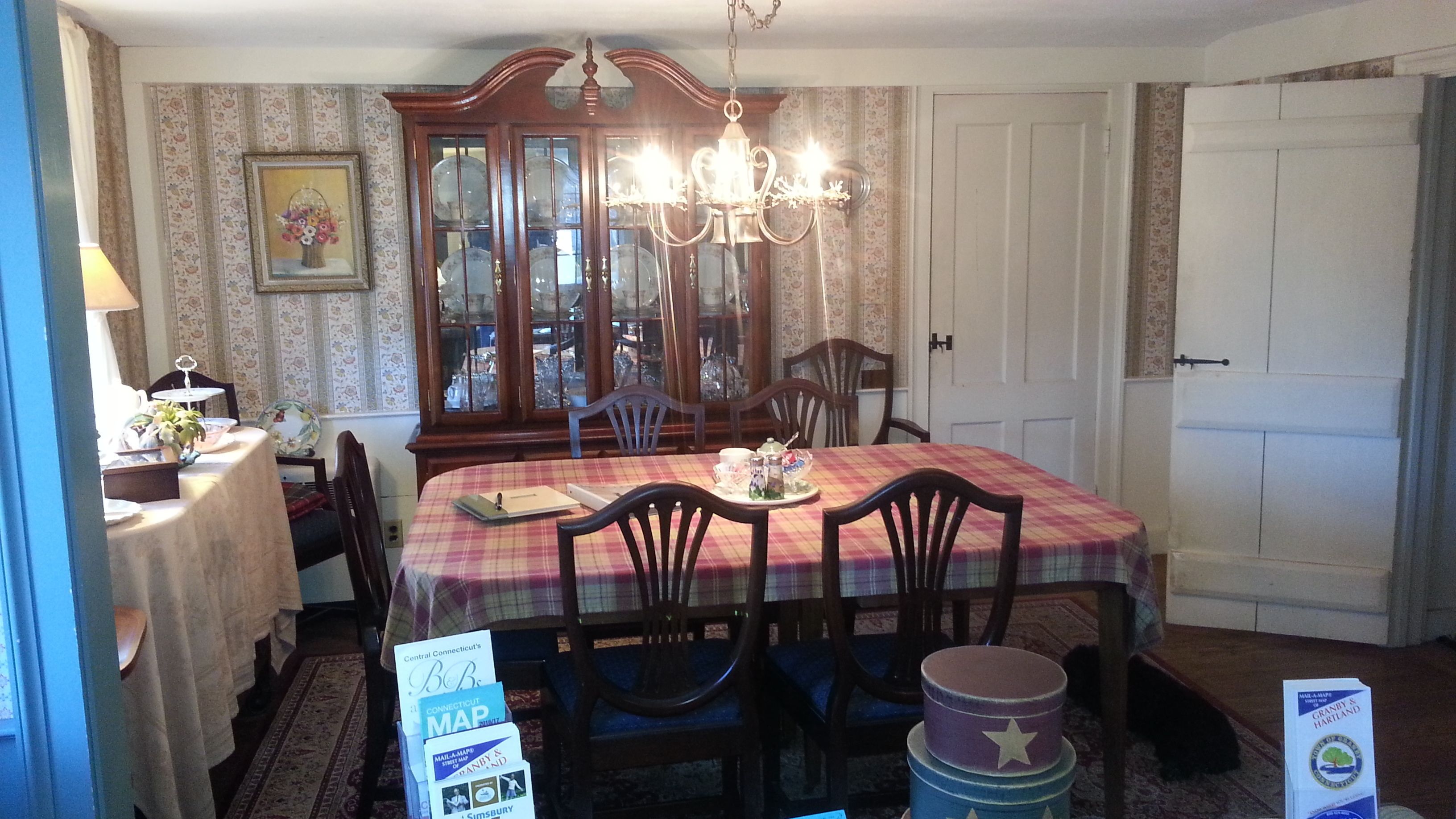 A dining area with a table set for four, a chandelier, and a cabinet with glass doors.
