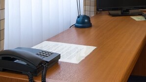 A wooden desk with a telephone, a computer monitor, and a piece of paper. - Landhotel Elkemann (Ahaus)