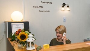 A reception desk with a framed welcome sign, a key rack, and a flower arrangement. - Landhotel Elkemann (Ahaus)