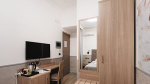 A hotel room with a wooden desk, a flat-screen TV, a bed with a wooden headboard, and a large mirror. - Affittacamere Centro Cavour (Rome)