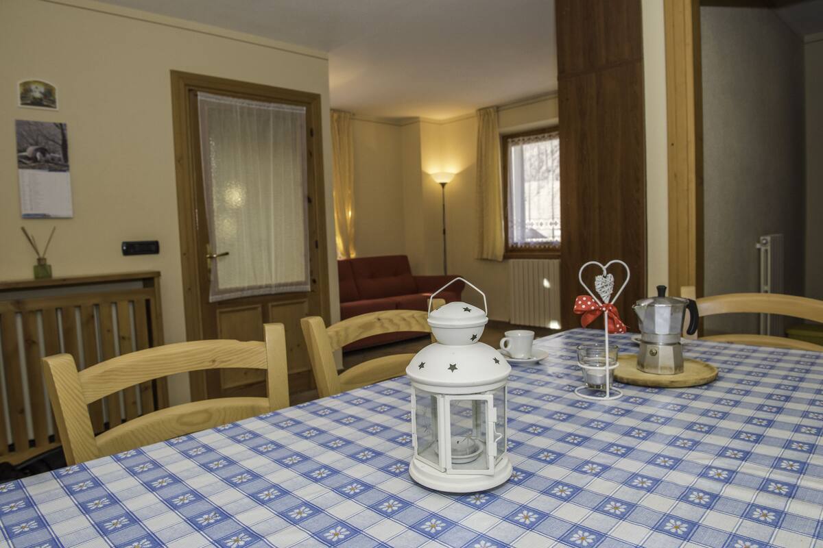 A dining area with a checkered tablecloth, a white lantern, and a coffee pot on a wooden table.