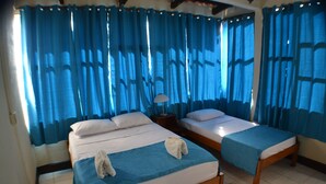 A hotel room with two beds, a nightstand, and a lamp. - Hotel Suyapa Beach (León)