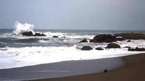 A beach with waves crashing against rocks and a sandy shore. - Hotel Suyapa Beach (León)