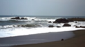 A beach with waves crashing against rocks and a clear sky. - Hotel Suyapa Beach (León)