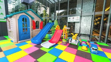 Kids can play and explore in this vibrant play area featuring a playhouse, slides, and a toy car.