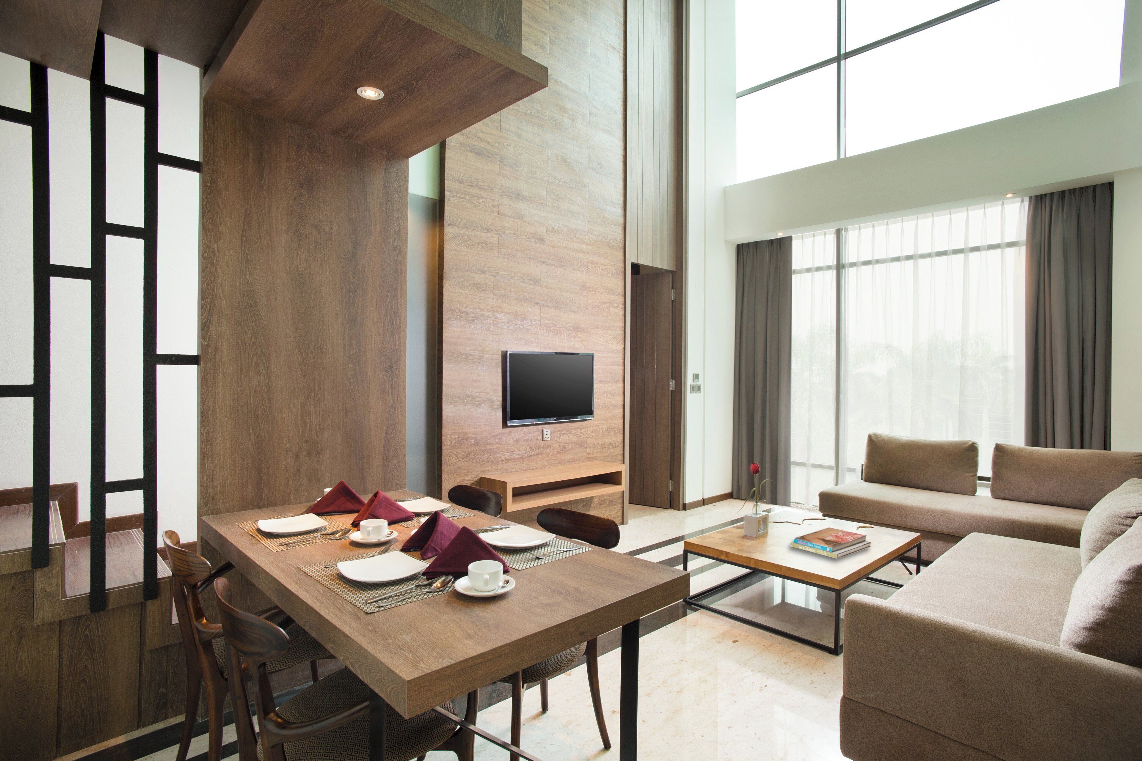 A modern hotel room with a dining area, a sofa, and a TV.