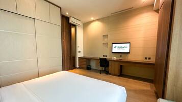 Una habitación de hotel con una cama, un escritorio, una silla y un televisor que muestra el logotipo de Holiday Inn.