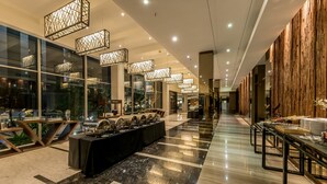 A modern hotel lobby with a long reception desk, glass walls, and contemporary lighting fixtures. - Holiday Inn Cikarang Jababeka by IHG (Cikarang)