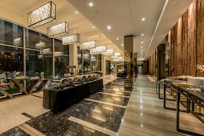 A modern hotel lobby with a long reception desk, glass walls, and contemporary lighting fixtures.