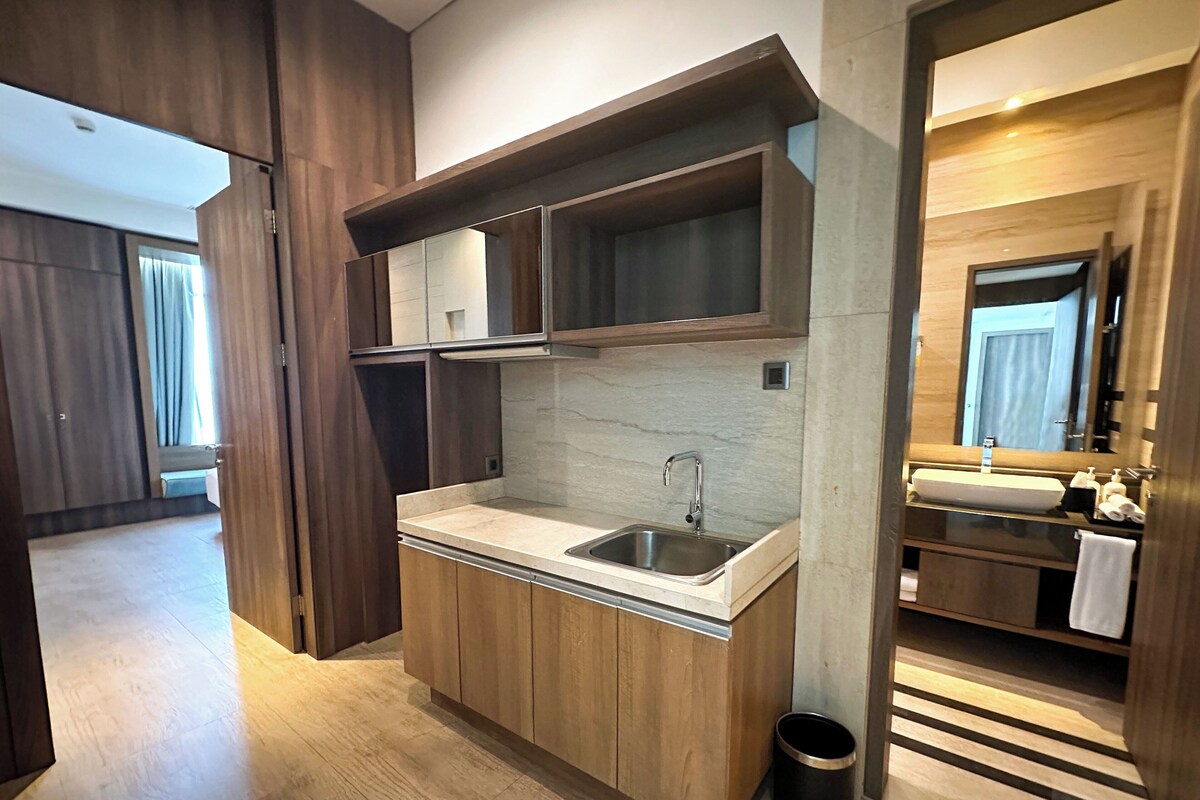 A modern kitchen with wooden cabinets, a stainless steel sink, and a marble backsplash.