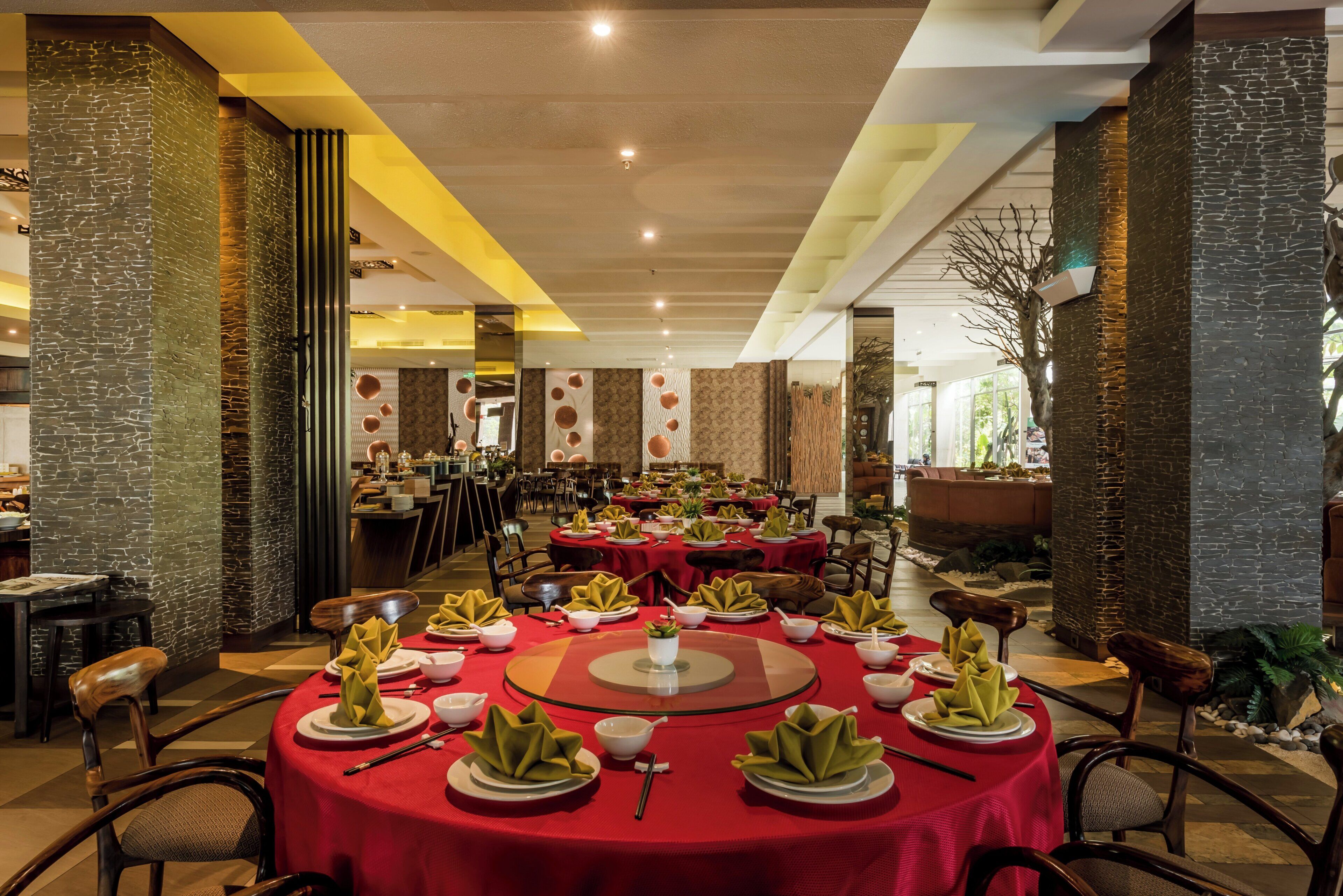 Un ristorante con tavoli rotondi apparecchiati per la cena, con un elemento decorativo al centro.