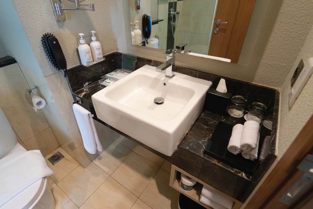 A bathroom with a white sink, a toilet, and a mirror above the sink.
