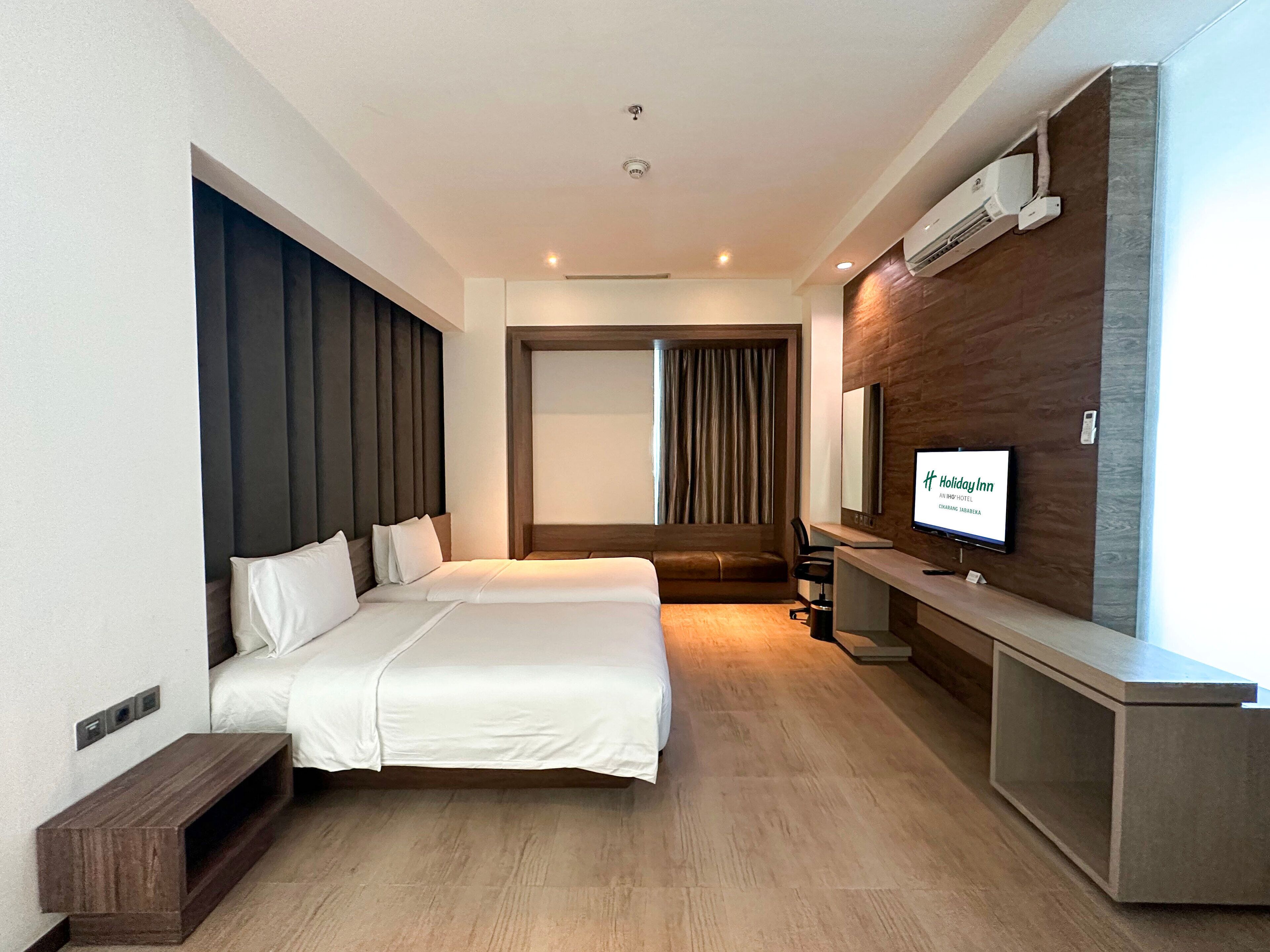 A hotel room with two beds, a TV, and a wooden wall.
