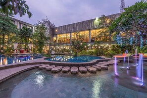 A pool area with multiple water features, seating areas, and lush greenery. - Holiday Inn Cikarang Jababeka by IHG (Cikarang)