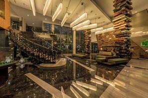 A modern lobby with a marble floor, a staircase with a unique railing design, and a central seating area with a stack of books as a decorative element. - Holiday Inn Cikarang Jababeka by IHG (Cikarang)